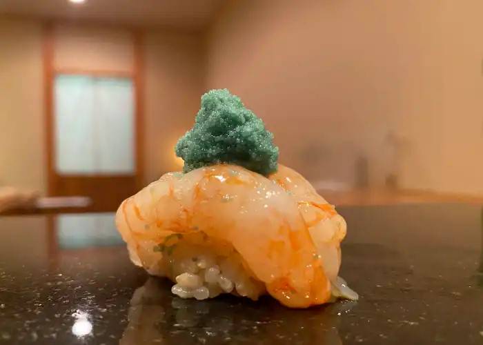 A serving of nigiri sushi at Sushi Shinosuke, delicately garnished with wasabi.